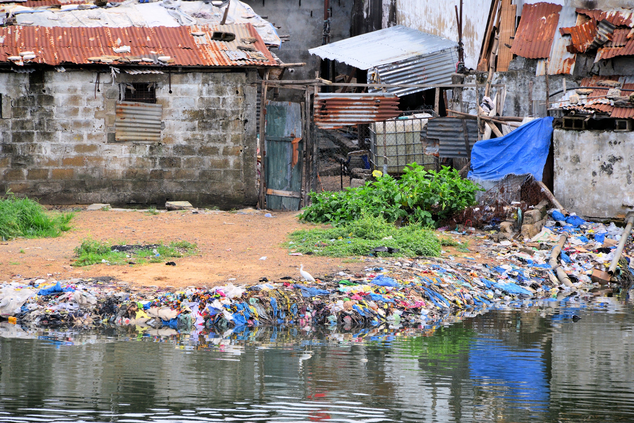 river with rubbish in it and a desolate house affected by pollution