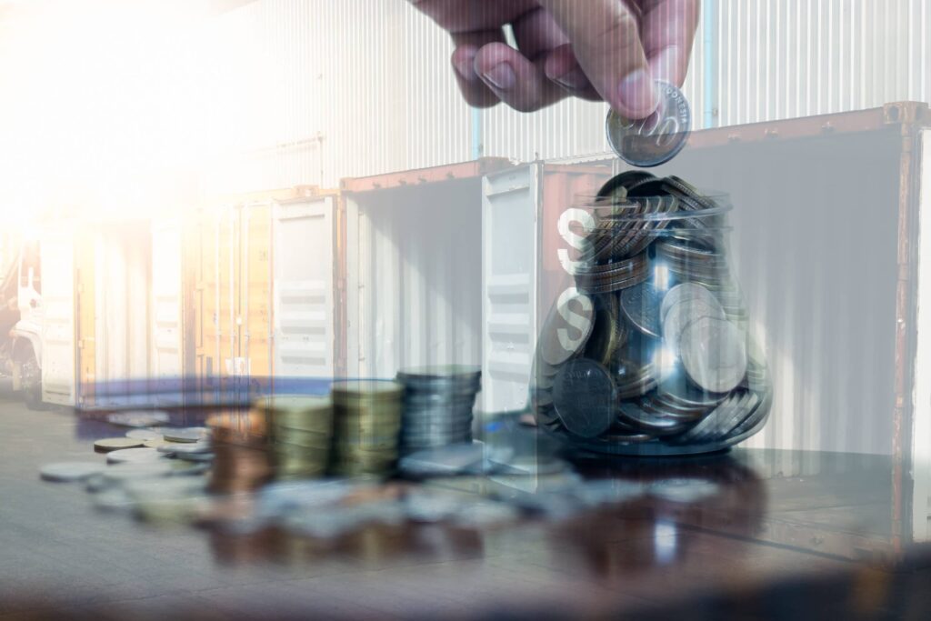 man putting coins into a jar with shipping containers in the background