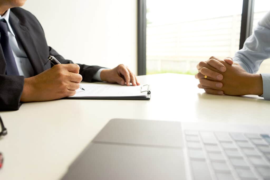 two people sat across form eachother at a desk, one interviewing the other in an investigation