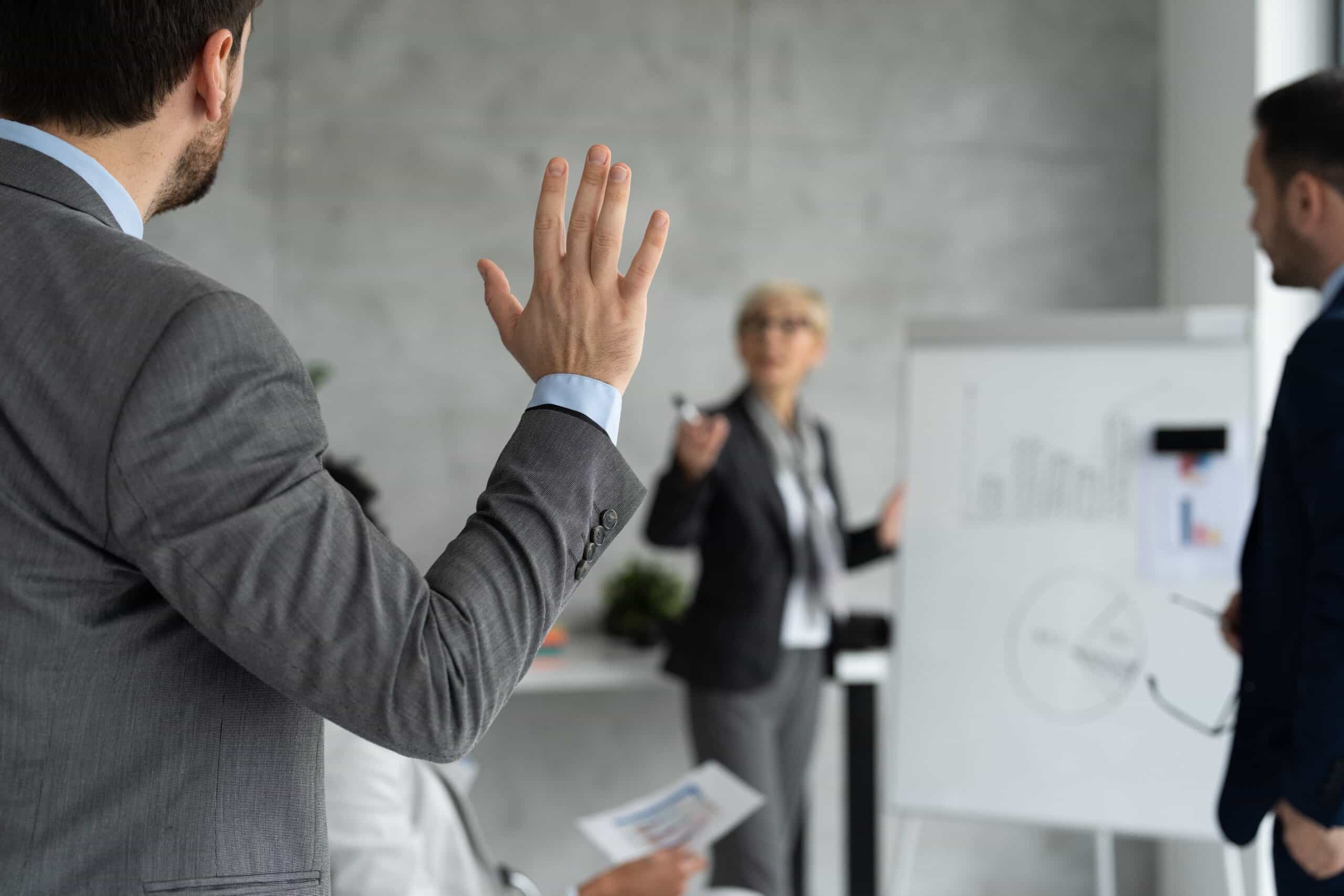 man putting his hand up in an office presentation