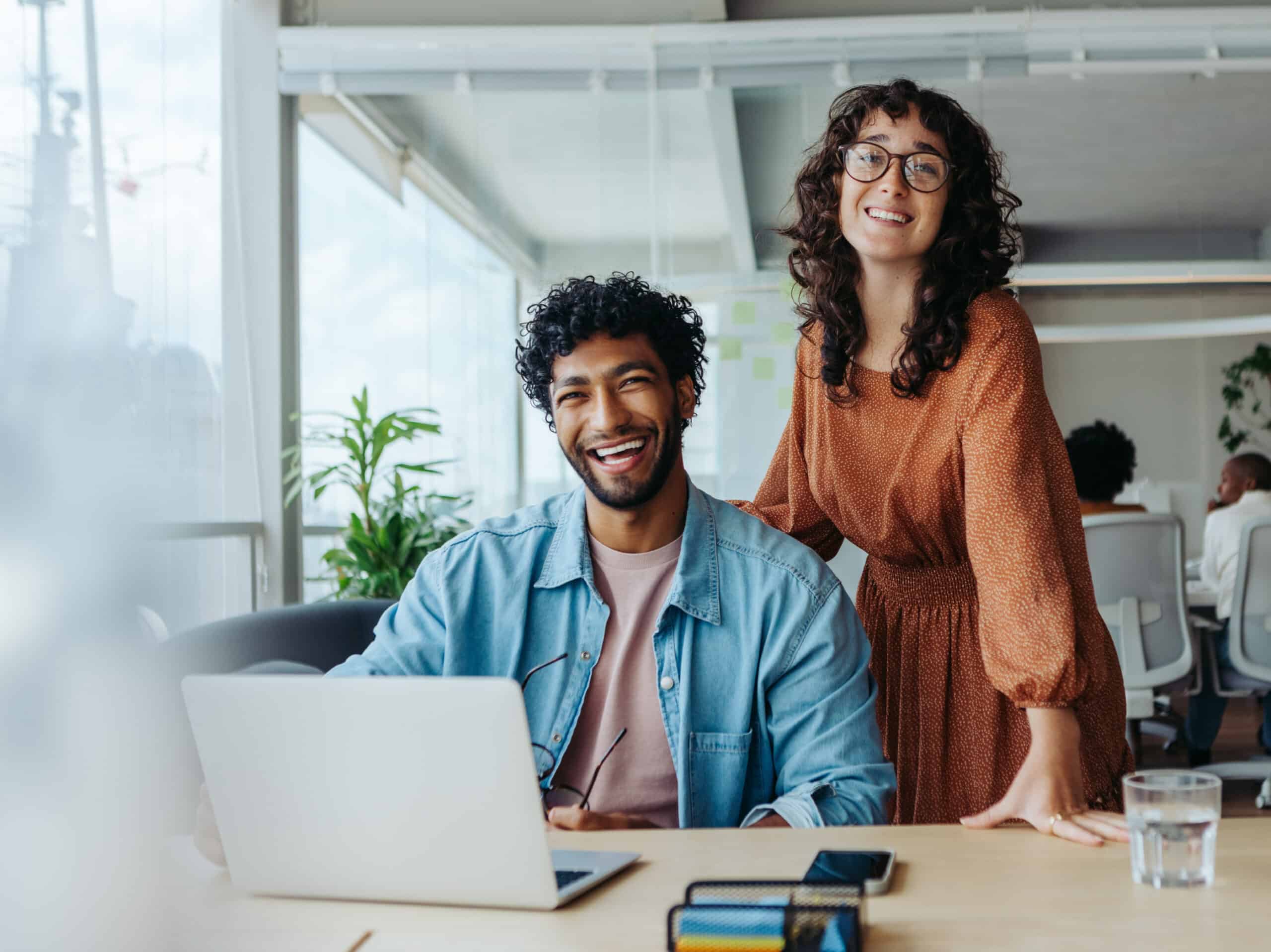 man and woman by an office desk working and smiling