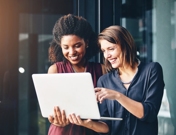 two women looking at a laptop laughing