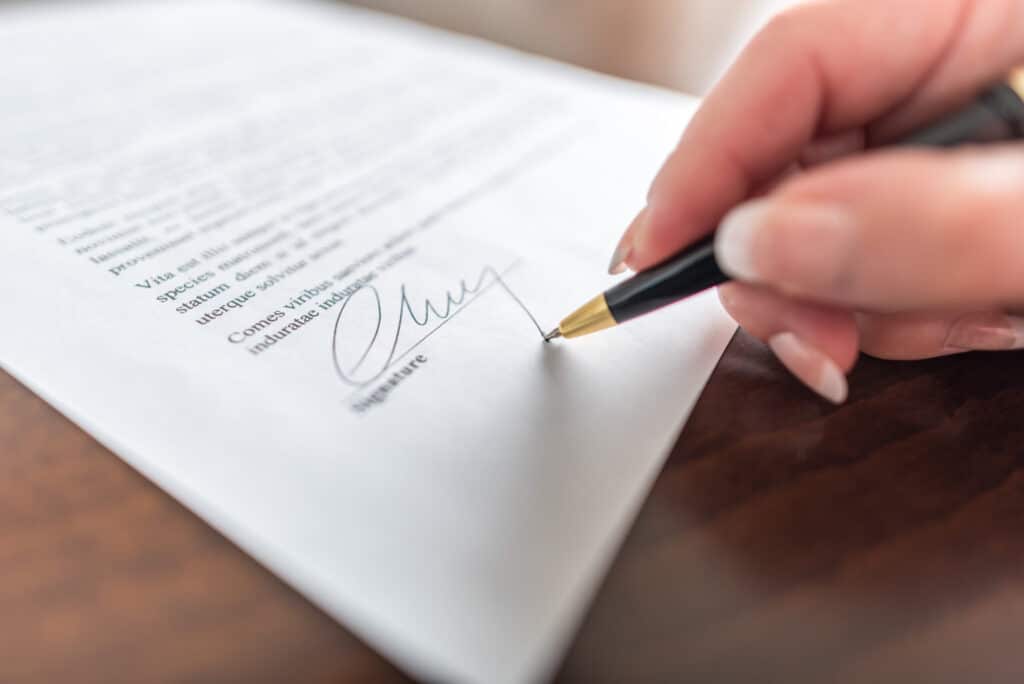 woman's hand signing a contract