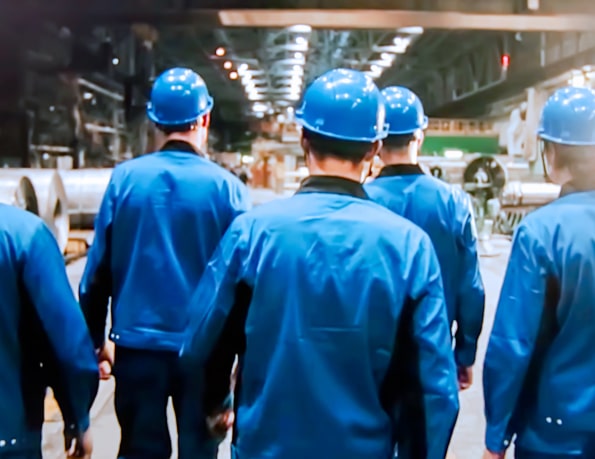 group of workers in blue PPE walking away from camera in a warehouse