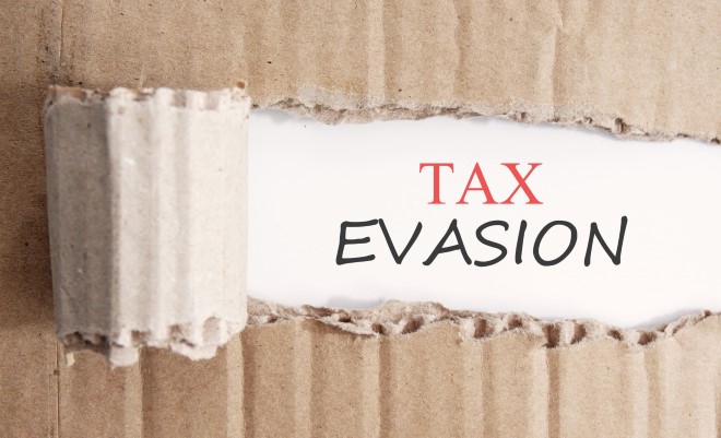 a piece of cardboard ripped revealing the text Tax evasion