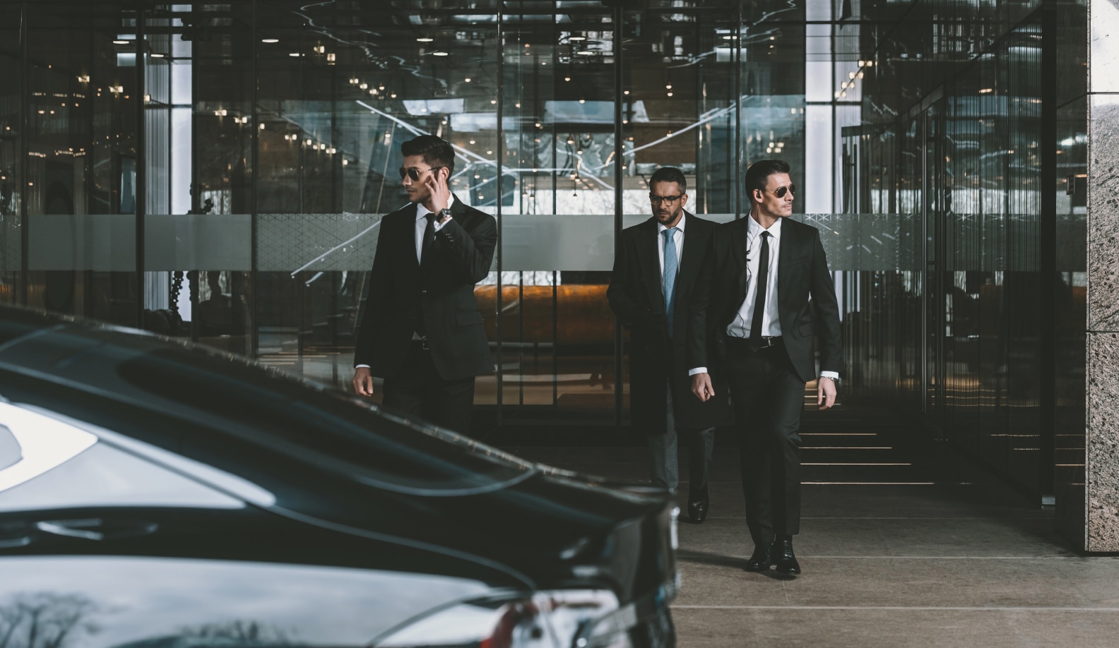 man being walked out of a building by two of his security guards