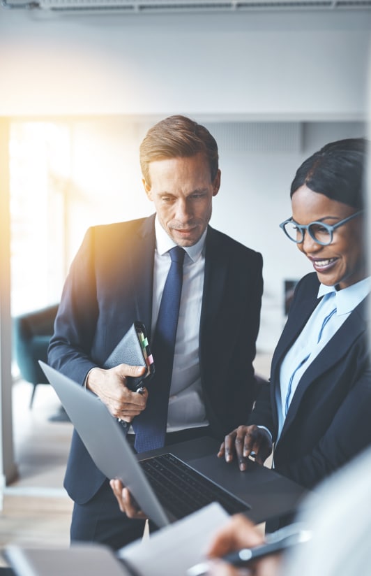 a man and a woman in suits working on a laptop