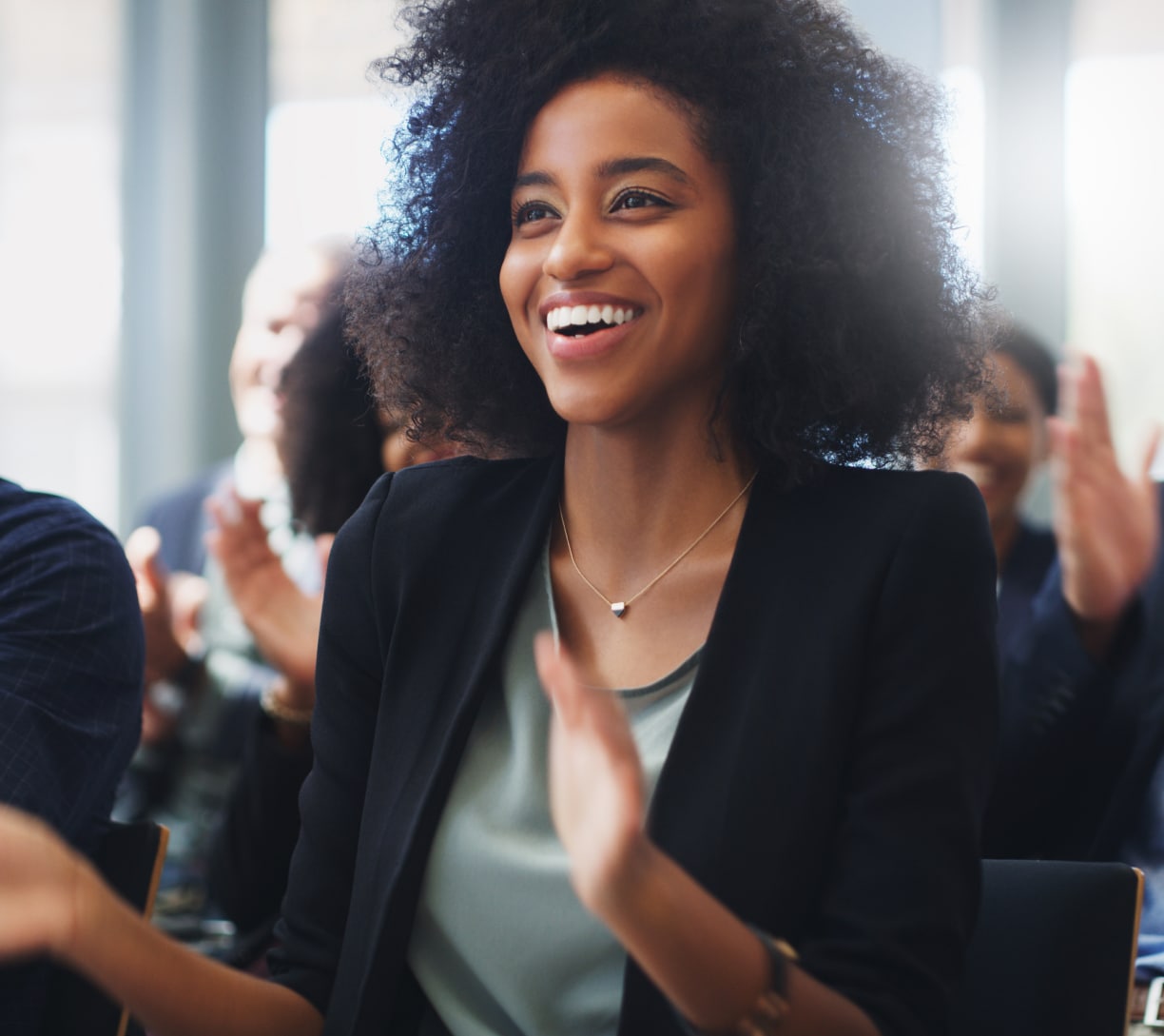 woman in the audience of a training presentation smiling and clapping