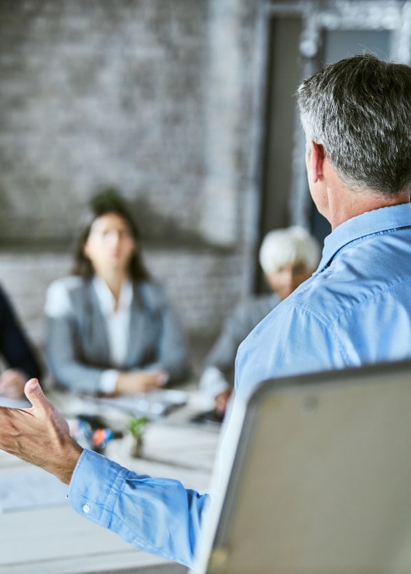 Back of a man who is leading a team meeting