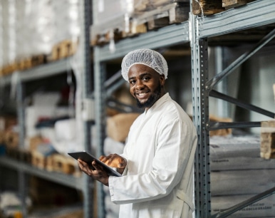 Man performing an assessment of a factory using a tablet device looking at the camera and smiling