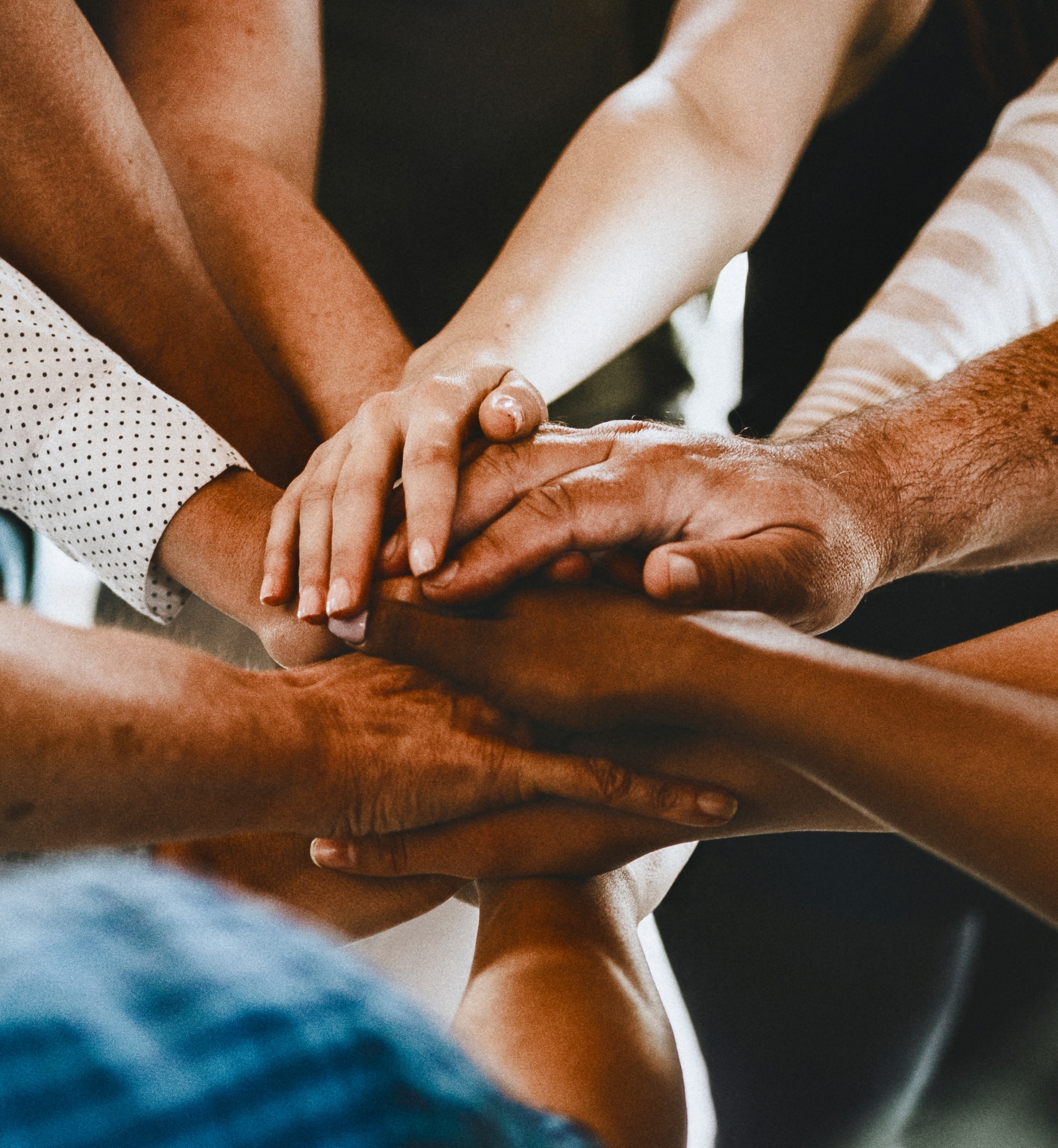 group of diverse people stacking their hands together in a circle