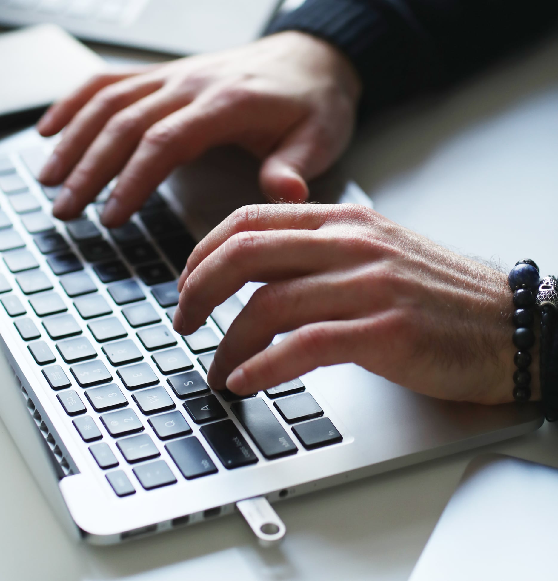 Close up of a man's hands typing on a laptop