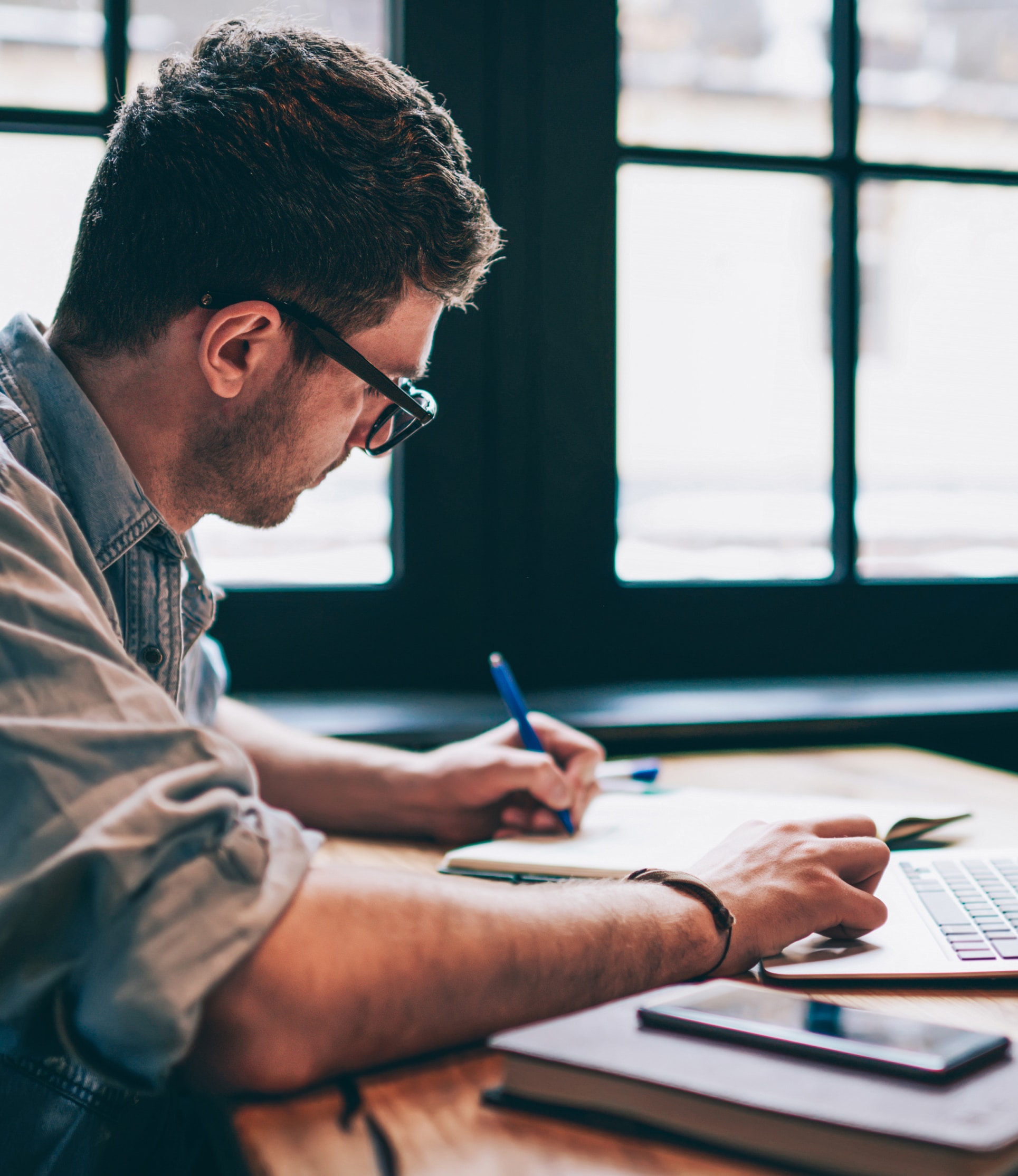 Man working at a desk writing in a notepad