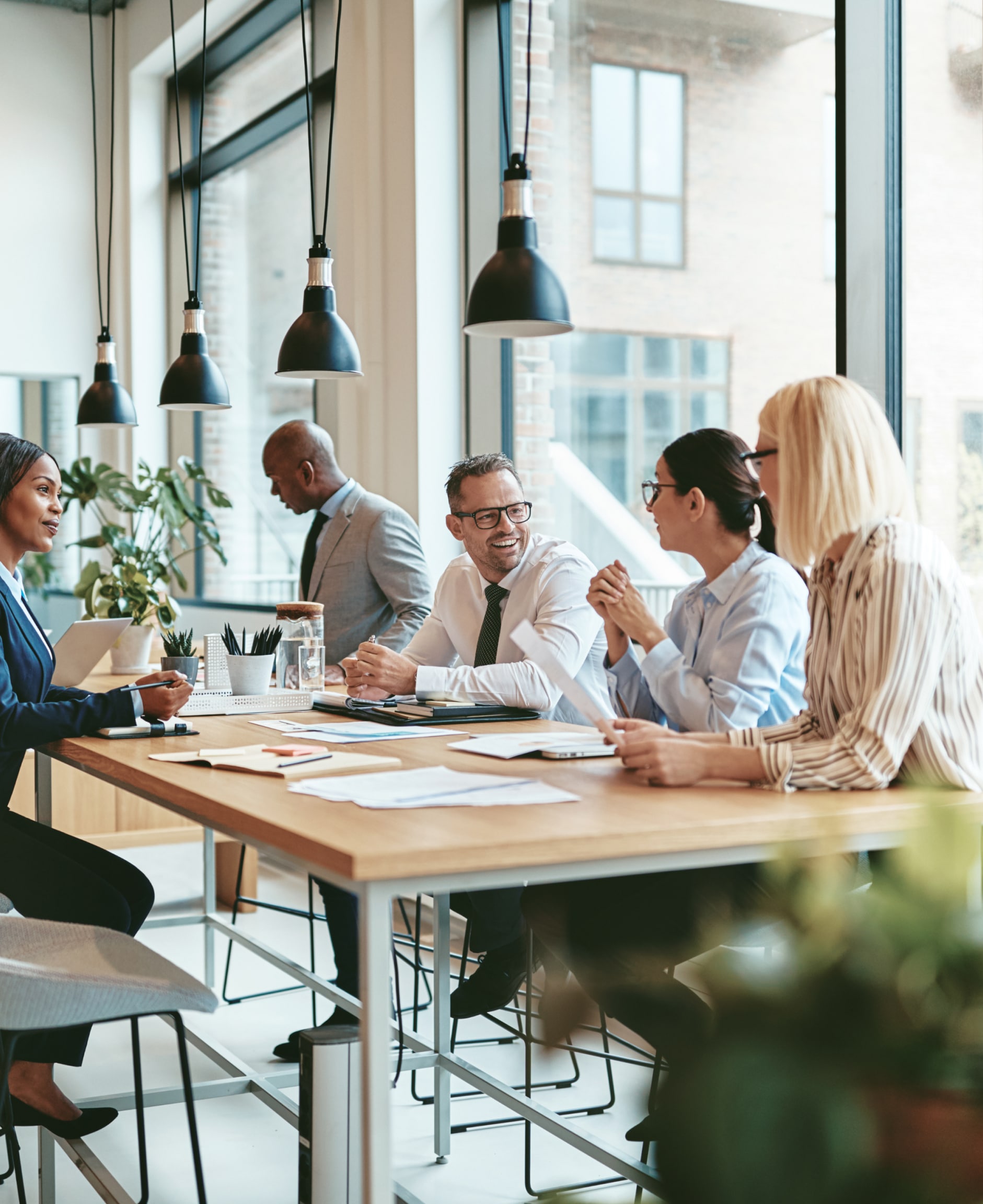 colleagues sat at a long office table talking and smiling