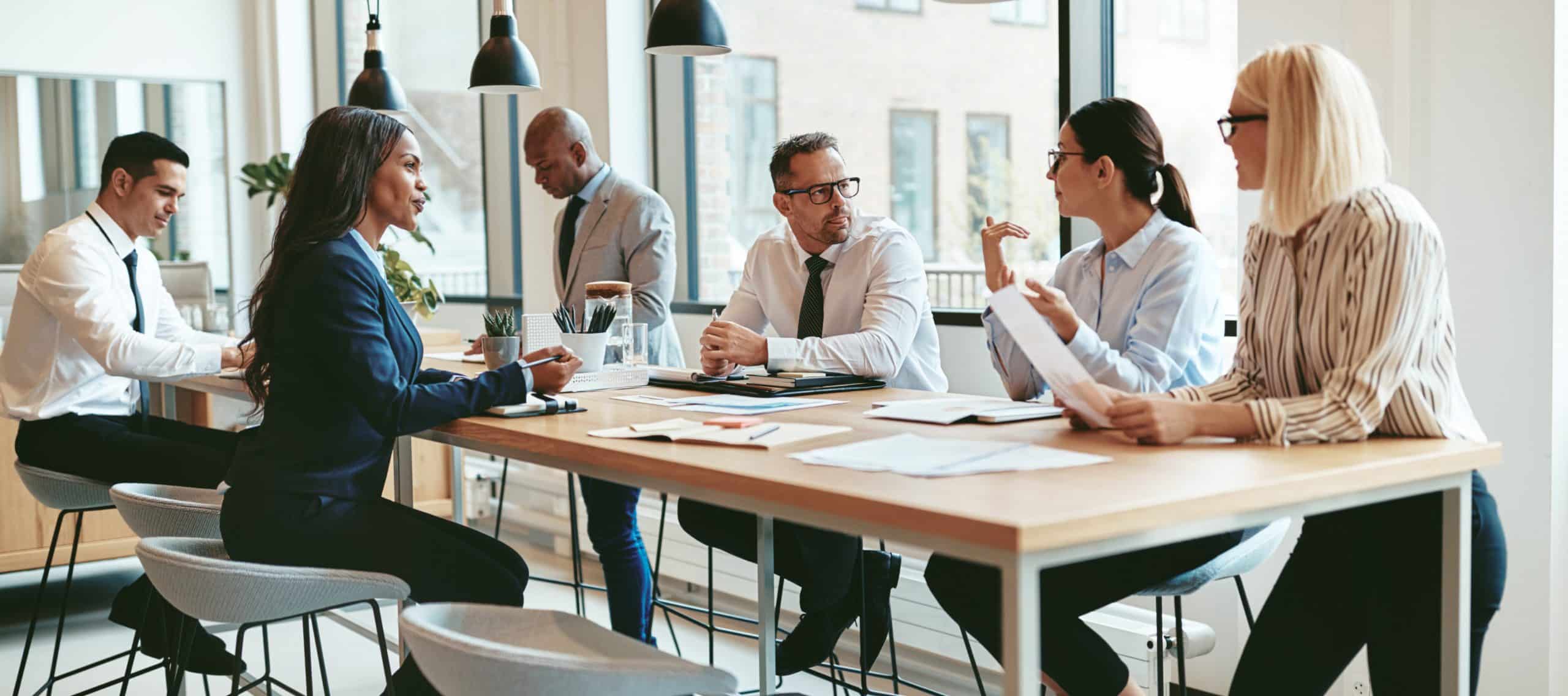 Group of smartly dressed people sat around a table having a discussion