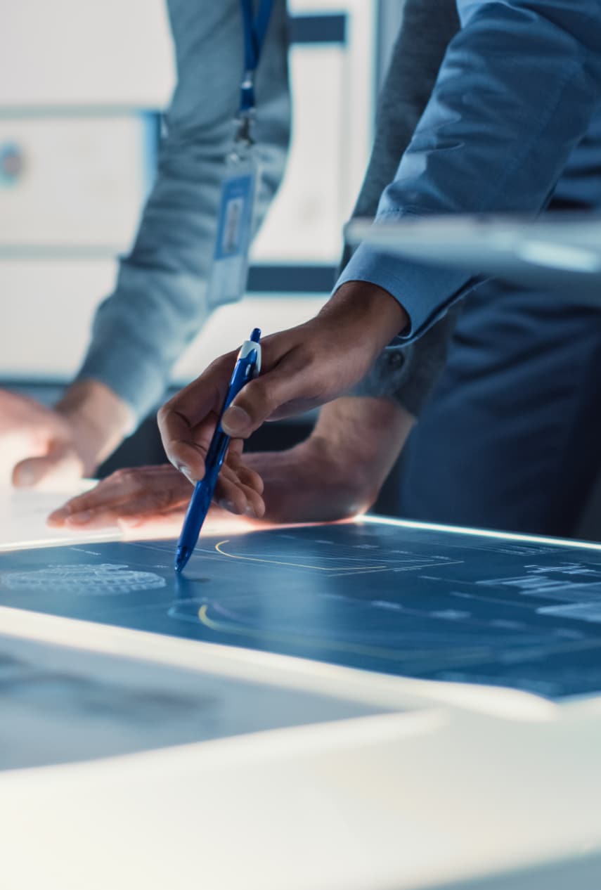 Man using a pen to point at a graph on a piece of paper that is on his desk