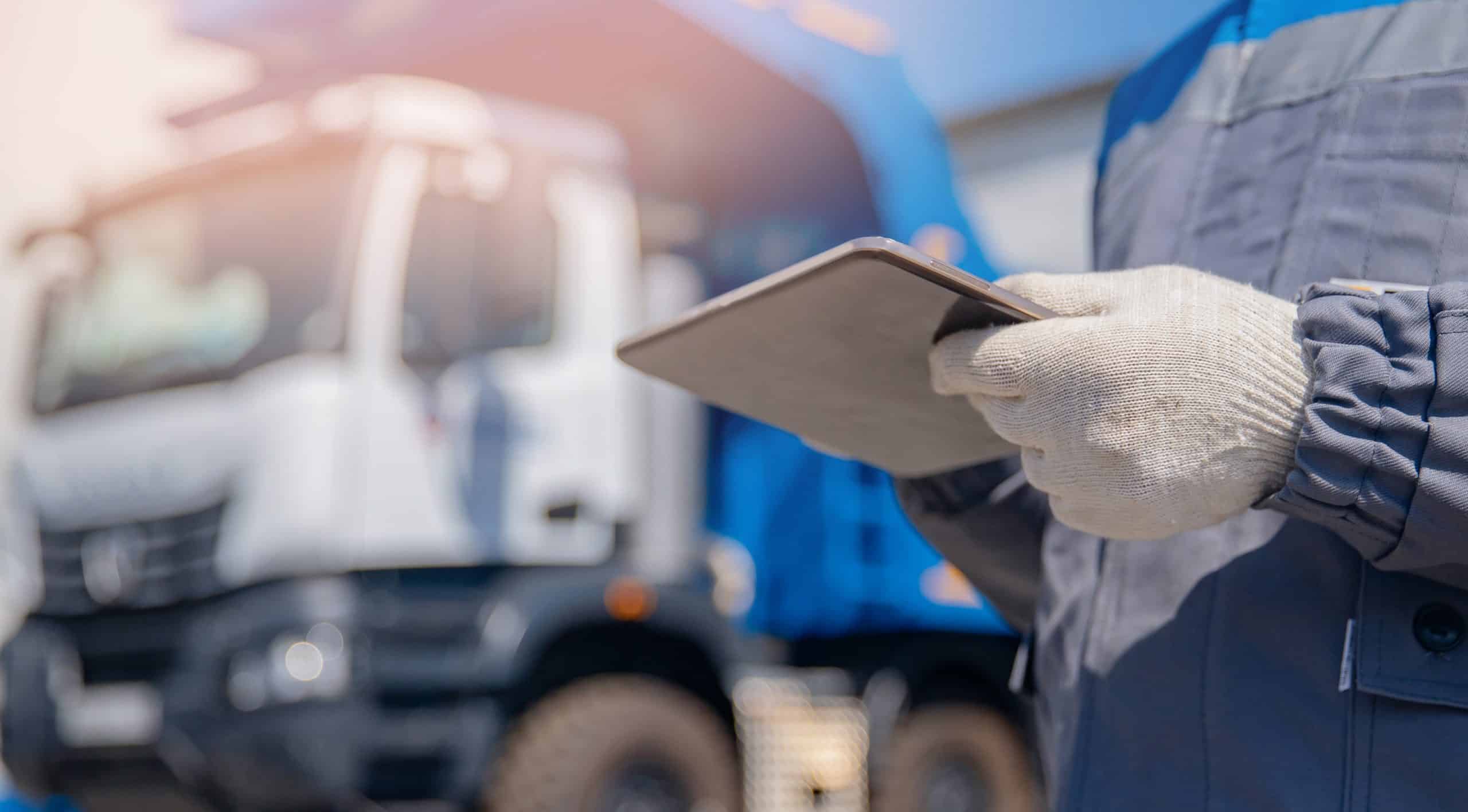 worker looking at a tablet device with lorry in the background