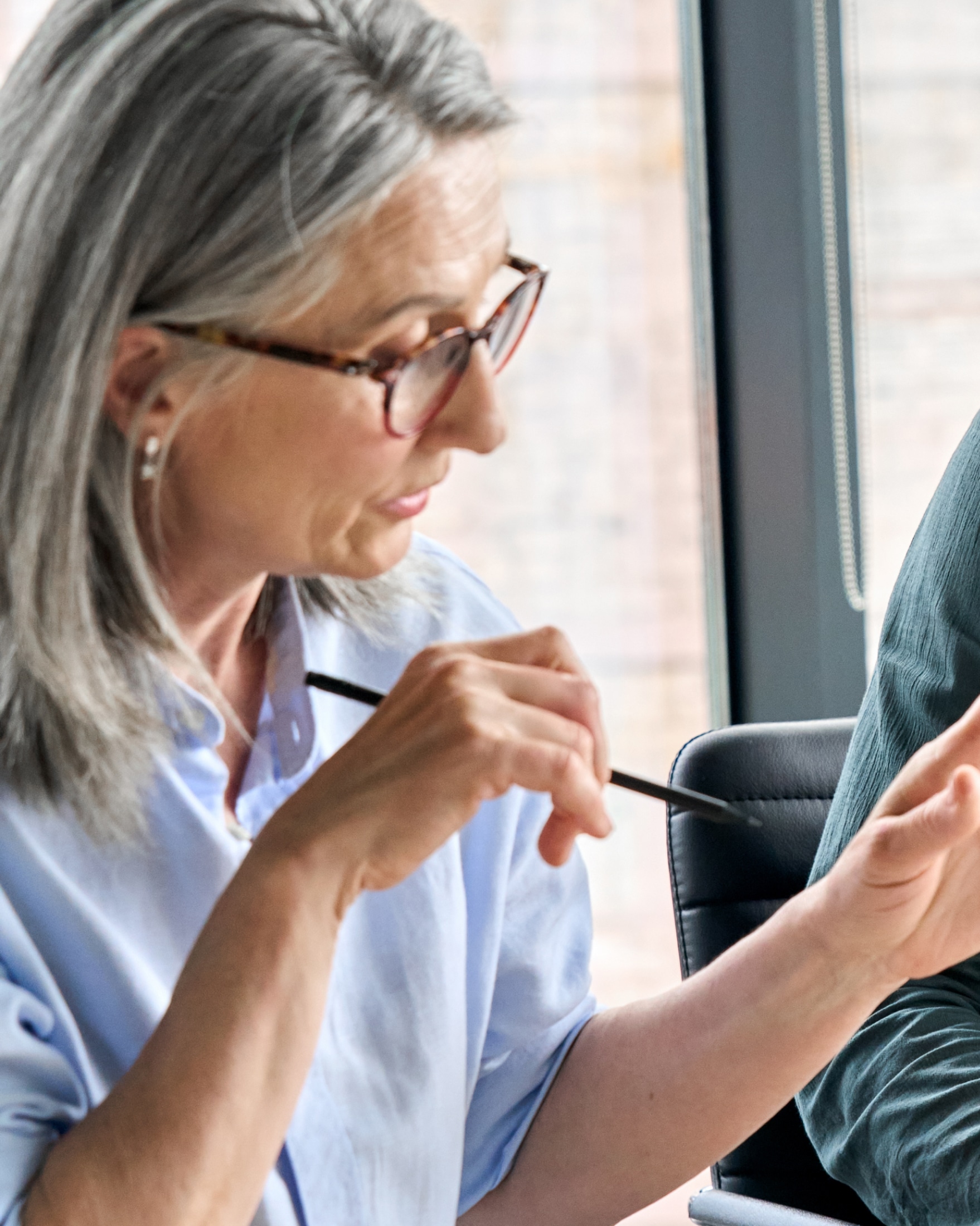 Woman wearing glasses holding a pencil in a meeting