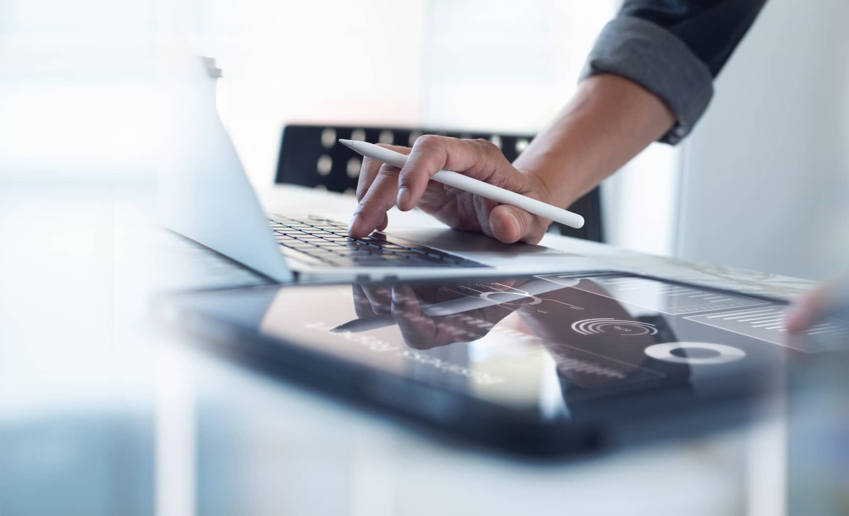 Close up of a man working on a tablet and laptop