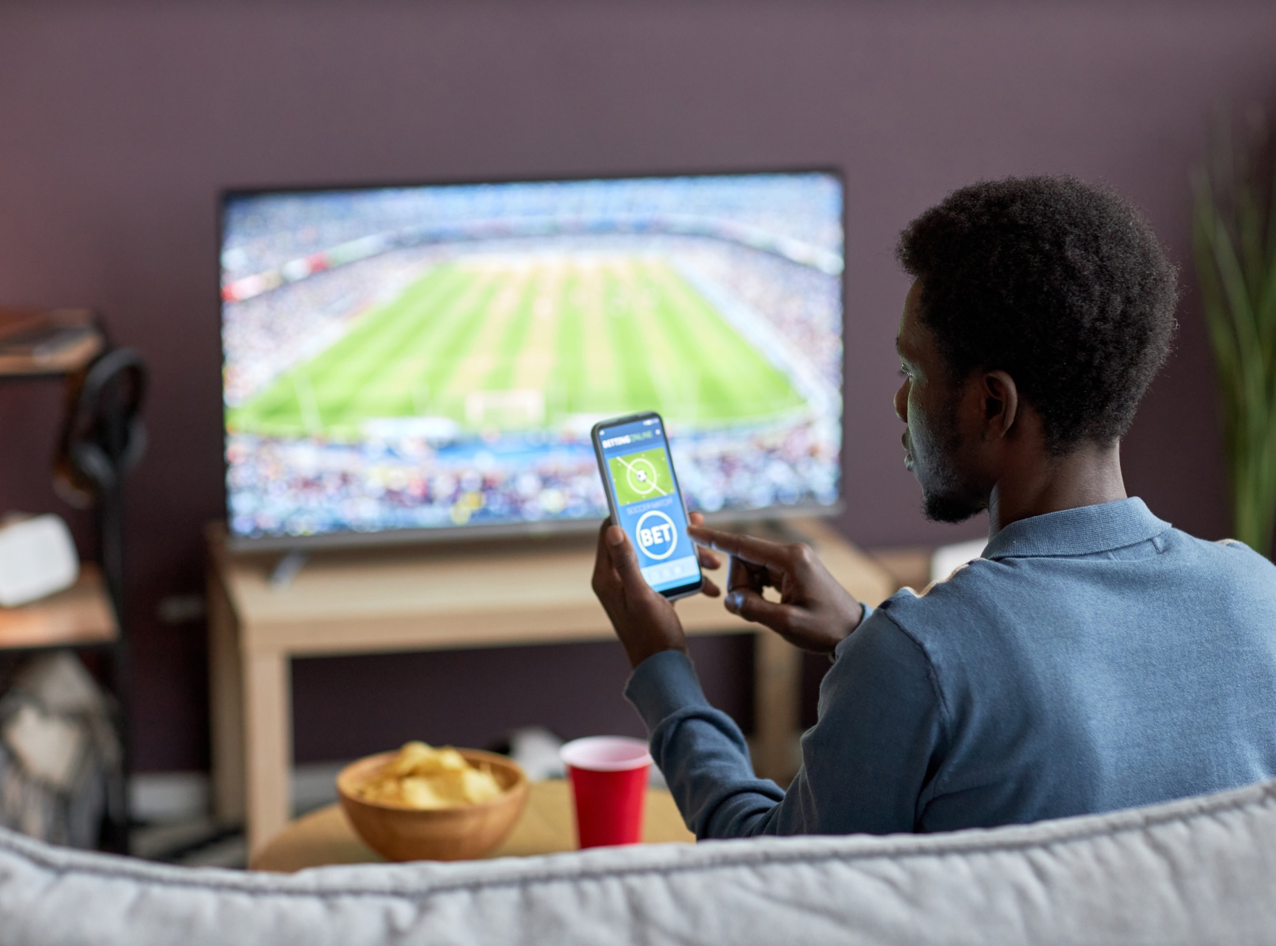 Man placing a bet on his phone for the football