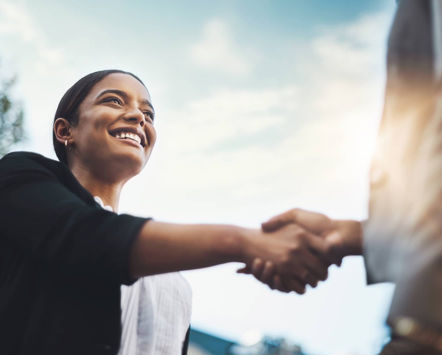 A woman shaking hands with someone and smiling