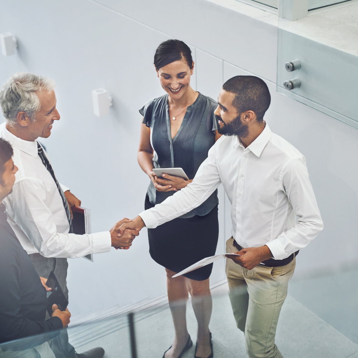 two smartly dressed men shaking hands in front of two other people