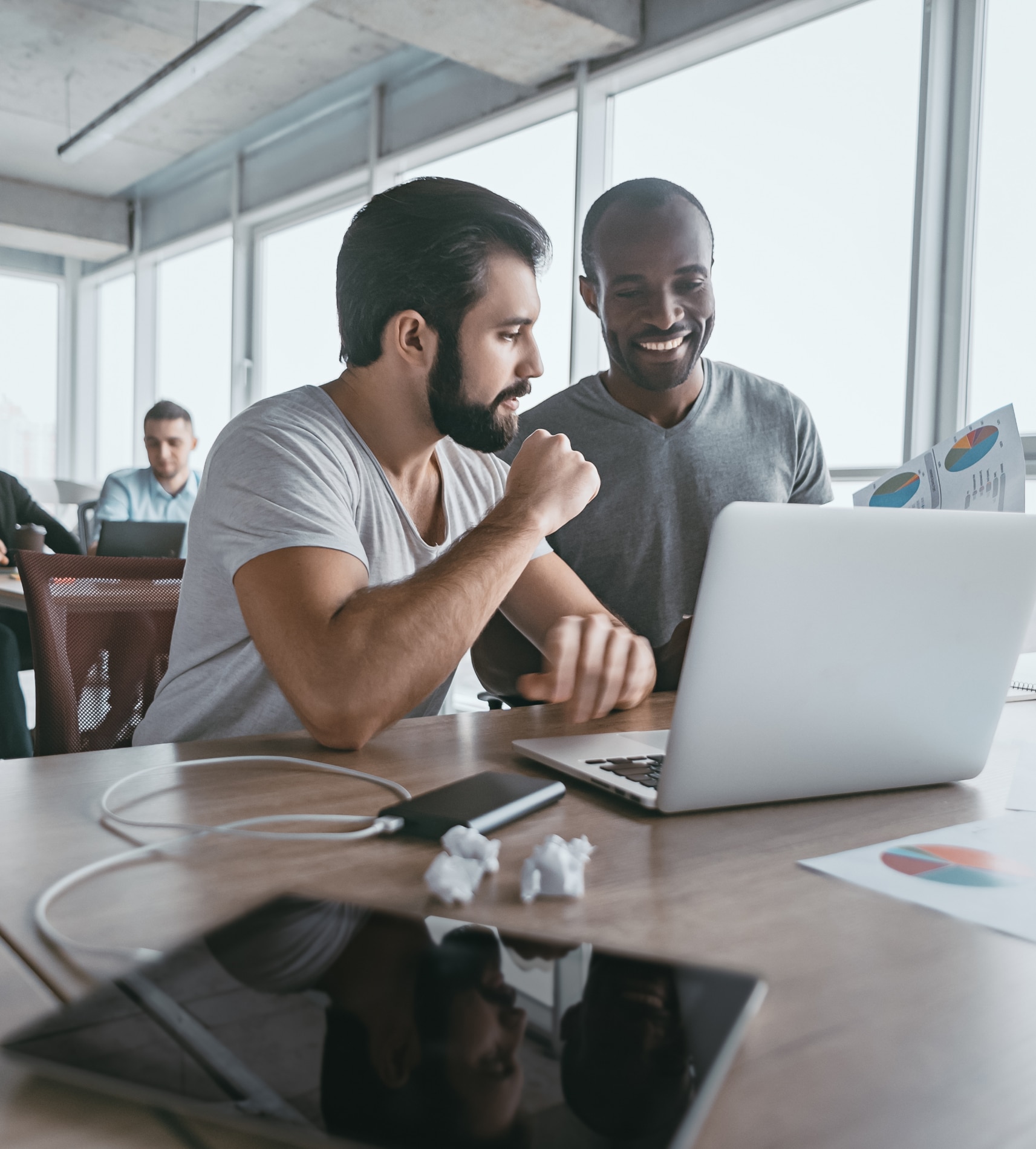 two young businessmen using a laptop to discuss a new project