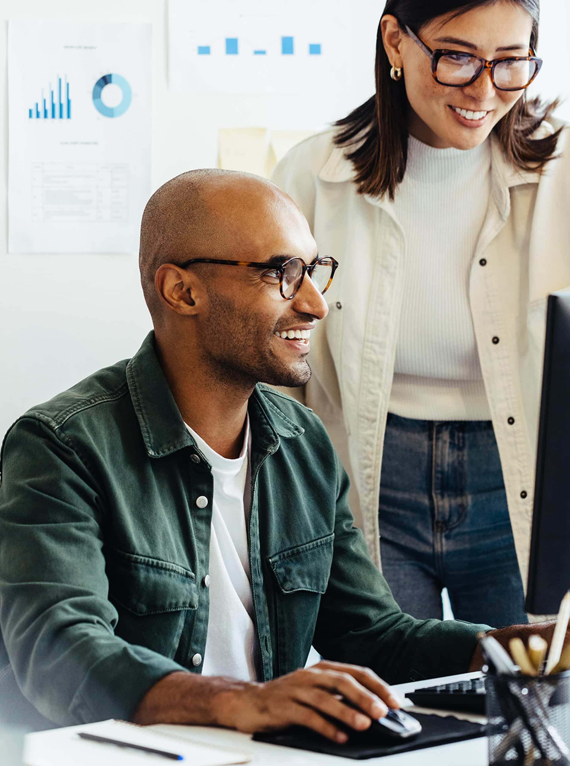 Man Sitting and woman standing by a computer working together