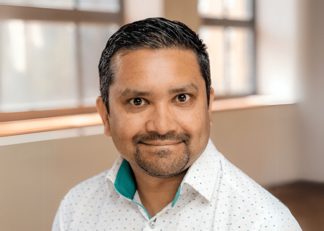 Smiling person in a bright room, wearing a shirt.