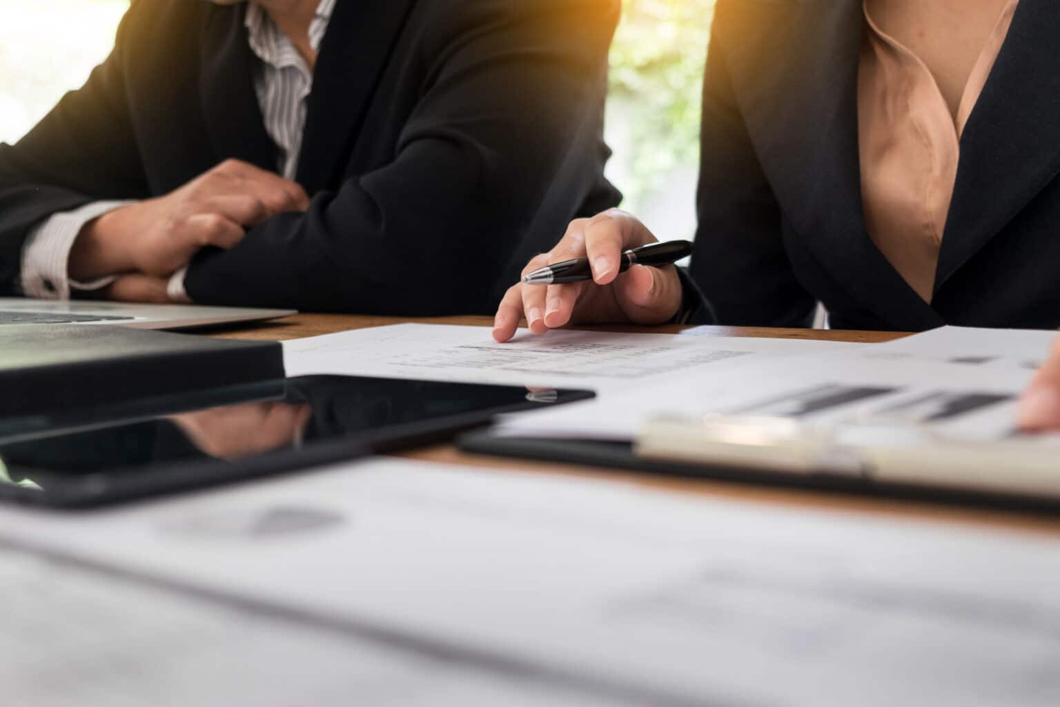 Business meeting with documents and tablet on table.